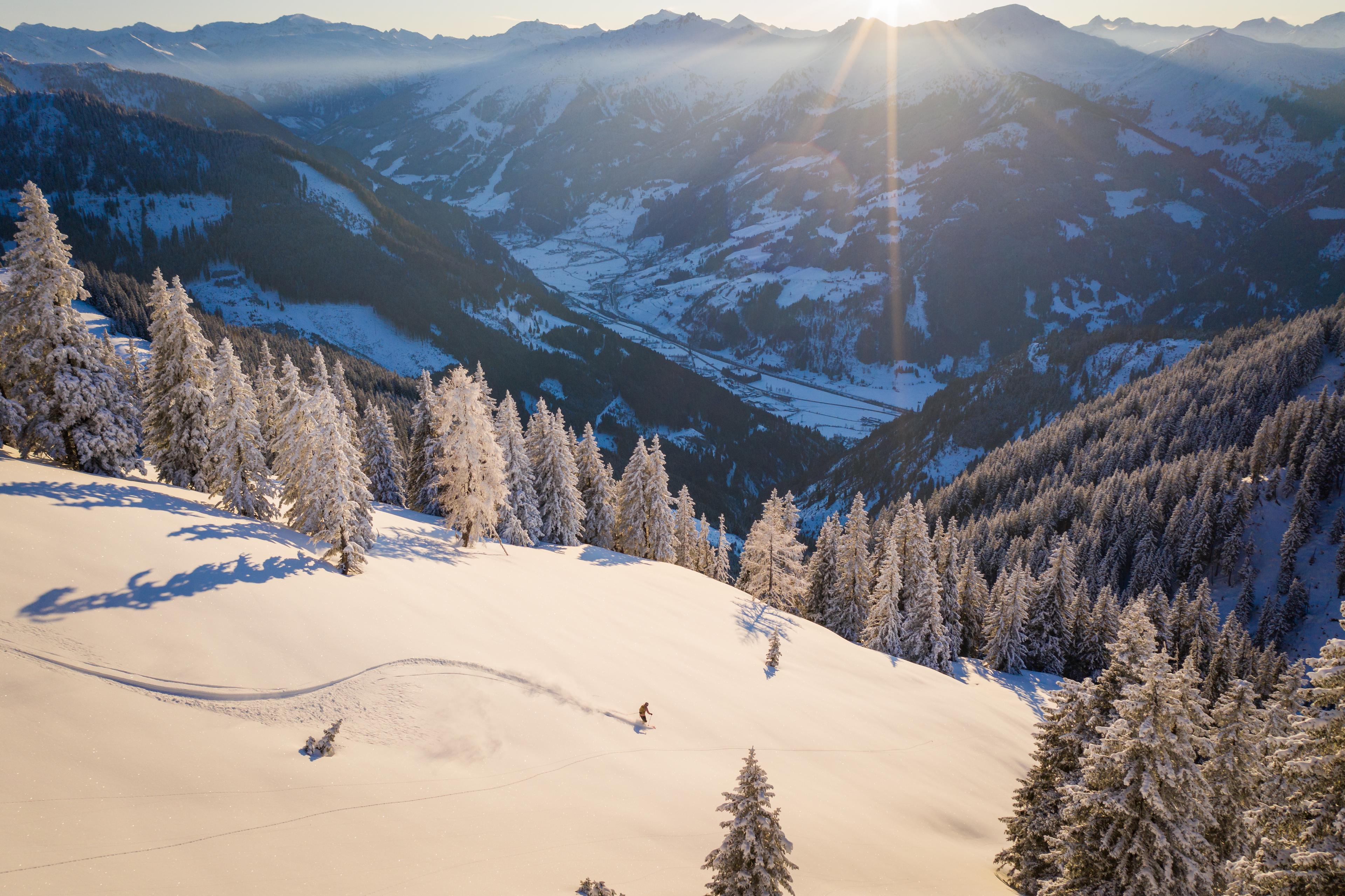 Skiier carving down off piste mountain at sunset